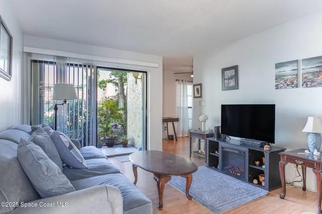 a living room with furniture a flat screen tv and a floor to ceiling window