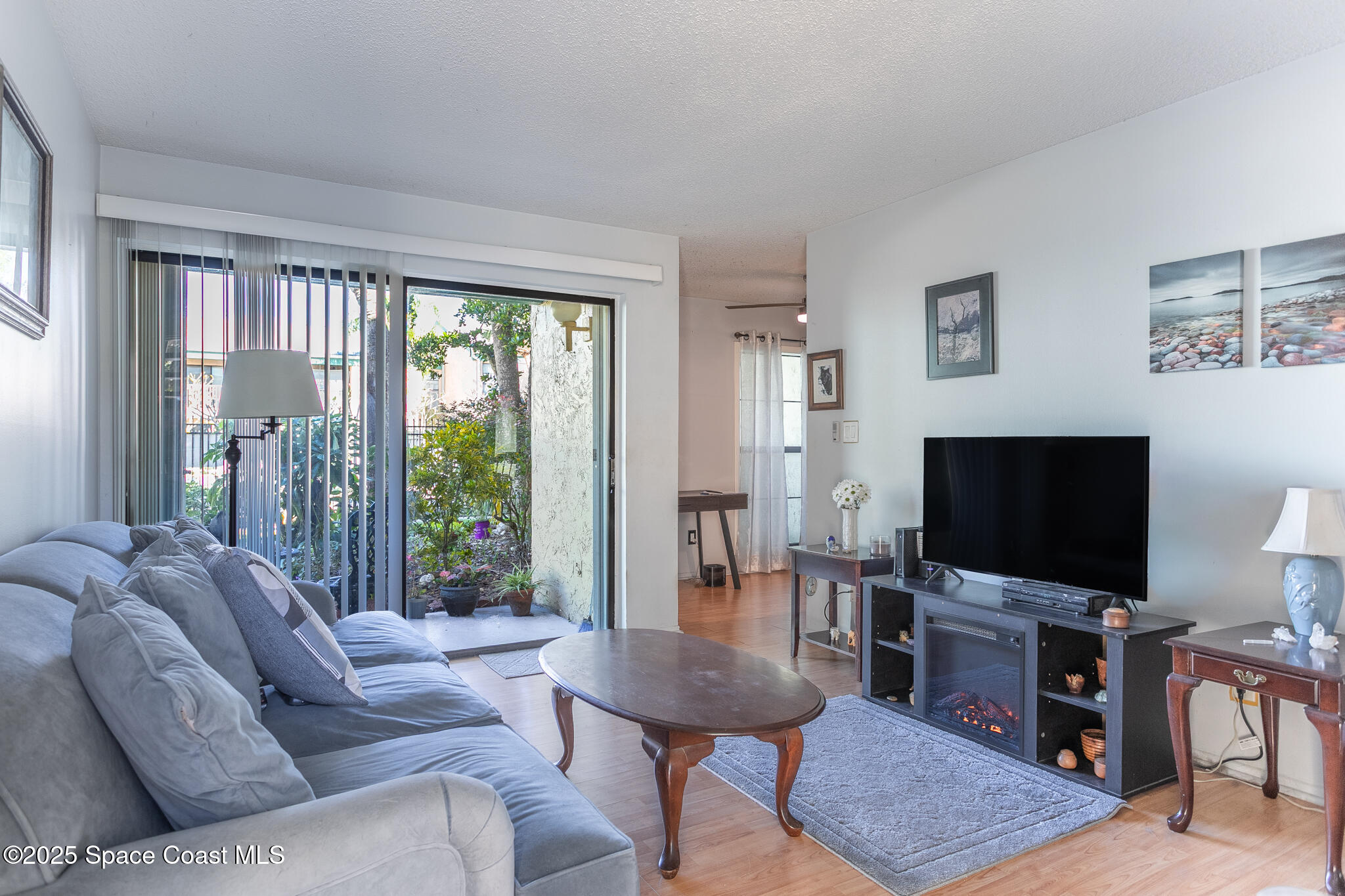 1225 North Wickham Road, Unit 712 Melbourne, FL 32935 - Photo 6 of 24 a living room with furniture a flat screen tv and a floor to ceiling window