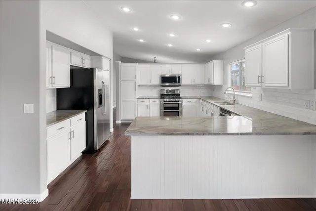 a large kitchen with granite countertop a large counter top stainless steel appliances and cabinets