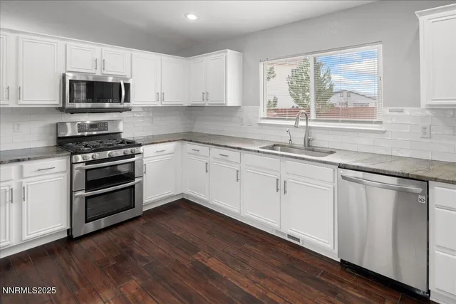 a kitchen with granite countertop white cabinets and a wooden floor