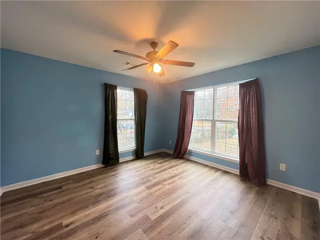 a view of an empty room with window and wooden floor
