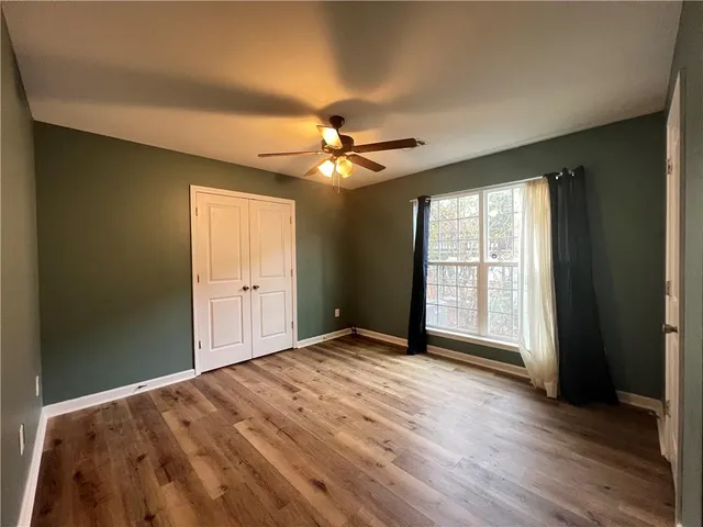 an empty room with wooden floor and fan