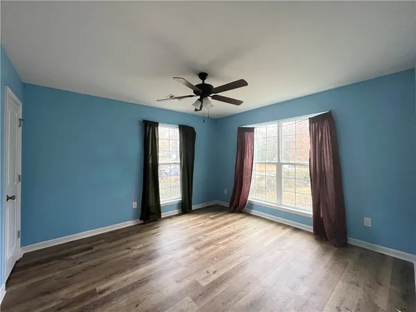 an empty room with wooden floor and ceiling fan