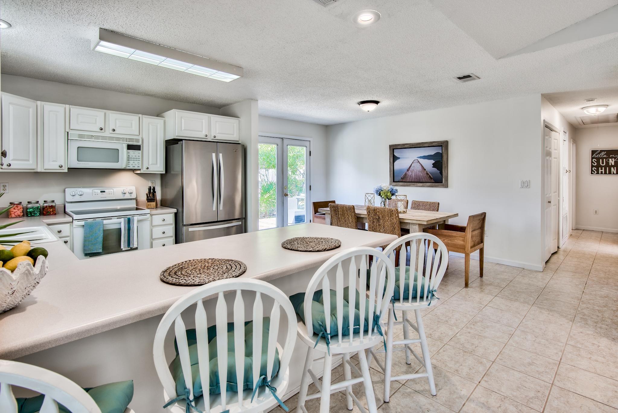 105 Ash Street Santa Rosa Beach, FL 32459 - Photo 6 of 43 a kitchen with stainless steel appliances wooden floor dining table and chairs