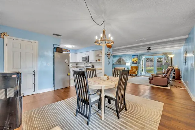 a dining room with furniture a chandelier and wooden floor