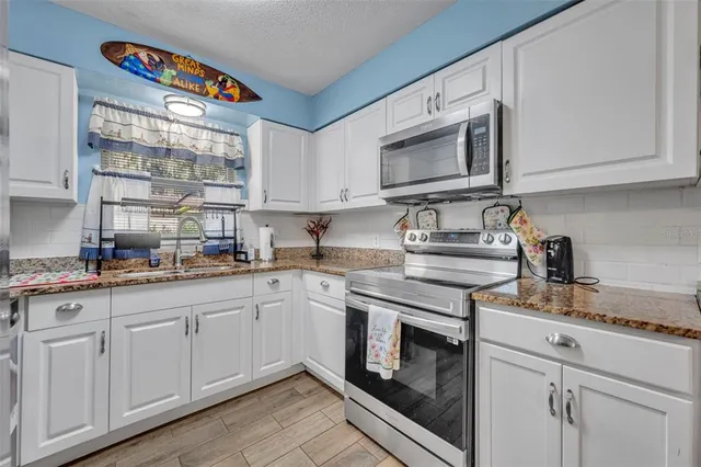 a kitchen with granite countertop white cabinets stainless steel appliances and a sink