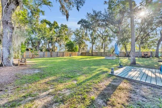 a view of yard with green space and trees in the background