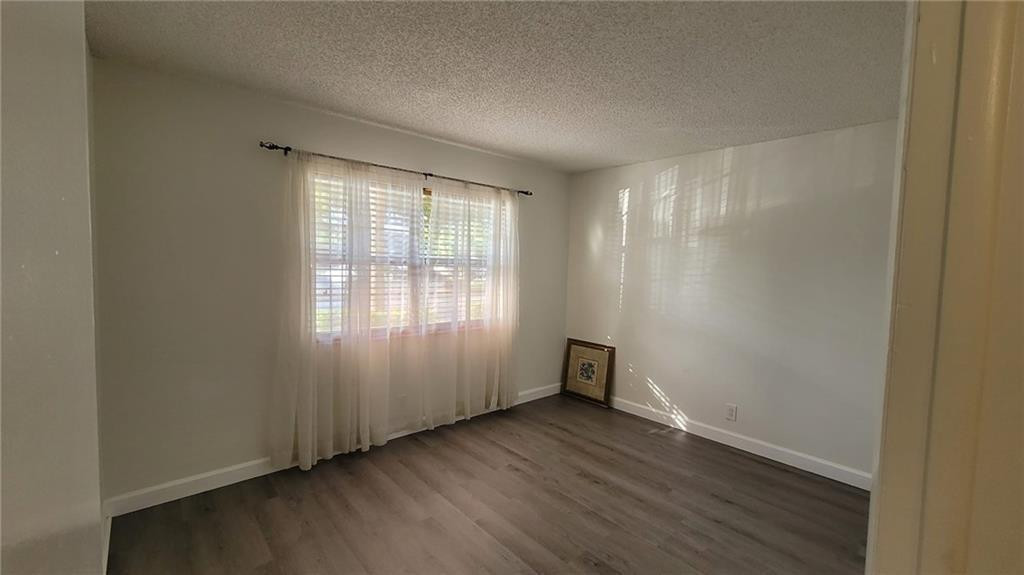 9273 Southwest 8th Street, Unit 109 Boca Raton, FL 33428 - Photo 2 of 20 an empty room with wooden floor and windows