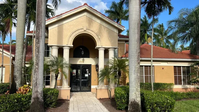 a view of white house with a small yard and plants