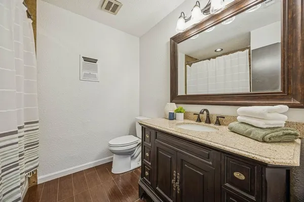 a bathroom with a granite countertop toilet sink and mirror