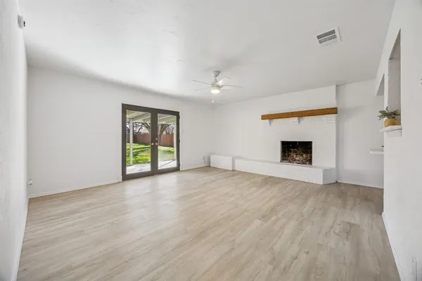 an empty room with windows and fireplace