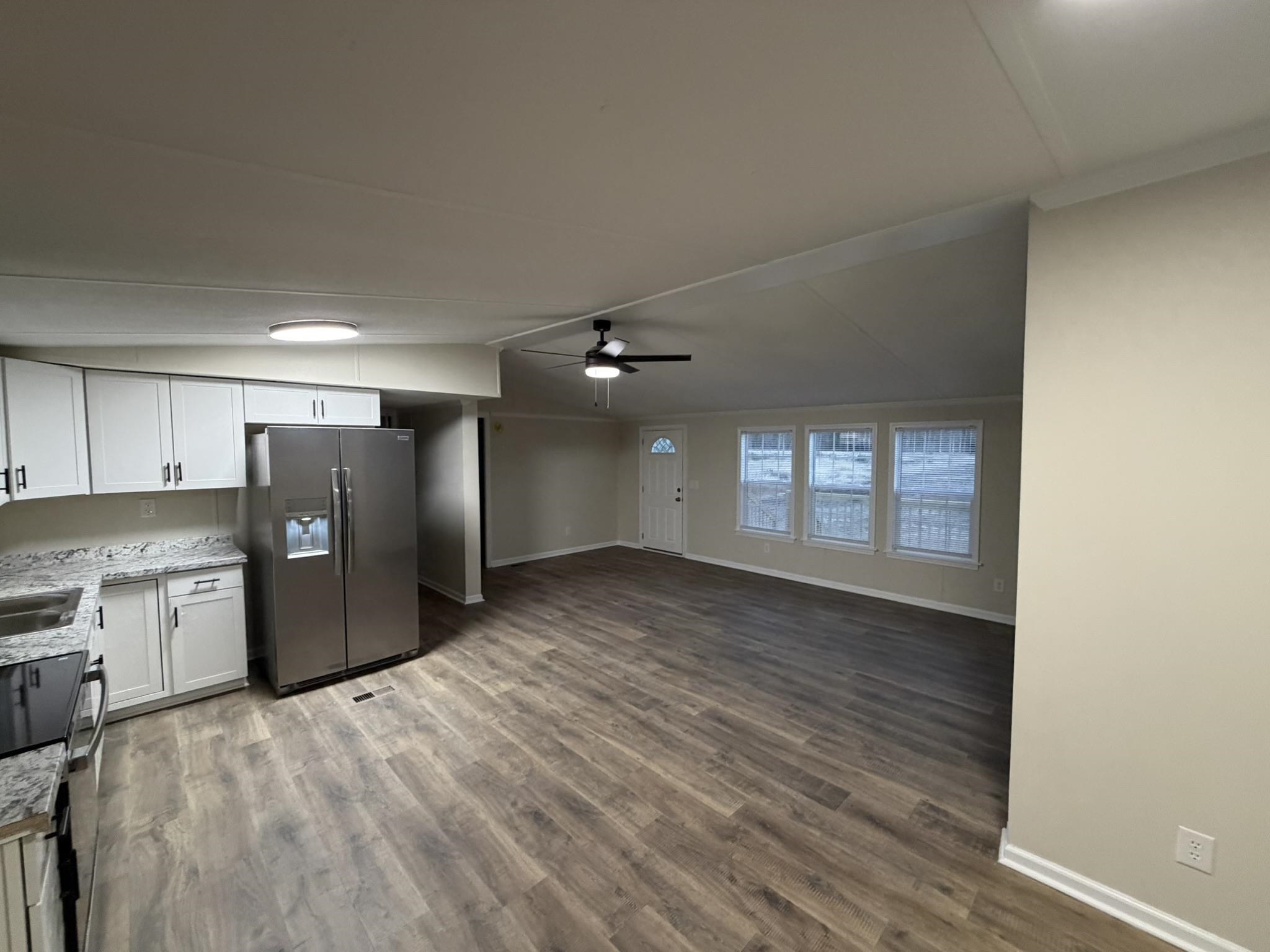 118 Nell Court Loris, SC 29569 - Photo 12 of 23 Kitchen with vaulted ceiling, white cabinets, appliances with stainless steel finishes, a ceiling fan, and dark wood-style flooring