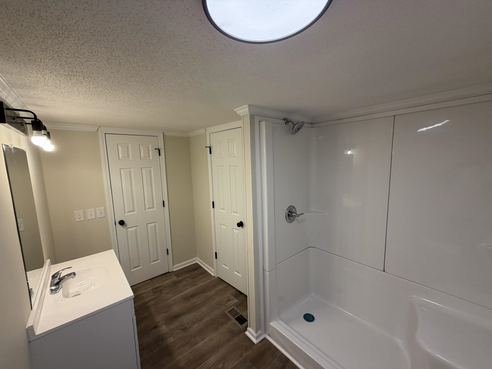 118 Nell Court Loris, SC 29569 - Photo 10 of 23 Bathroom with vanity, a textured ceiling, a shower stall, and dark wood finished floors