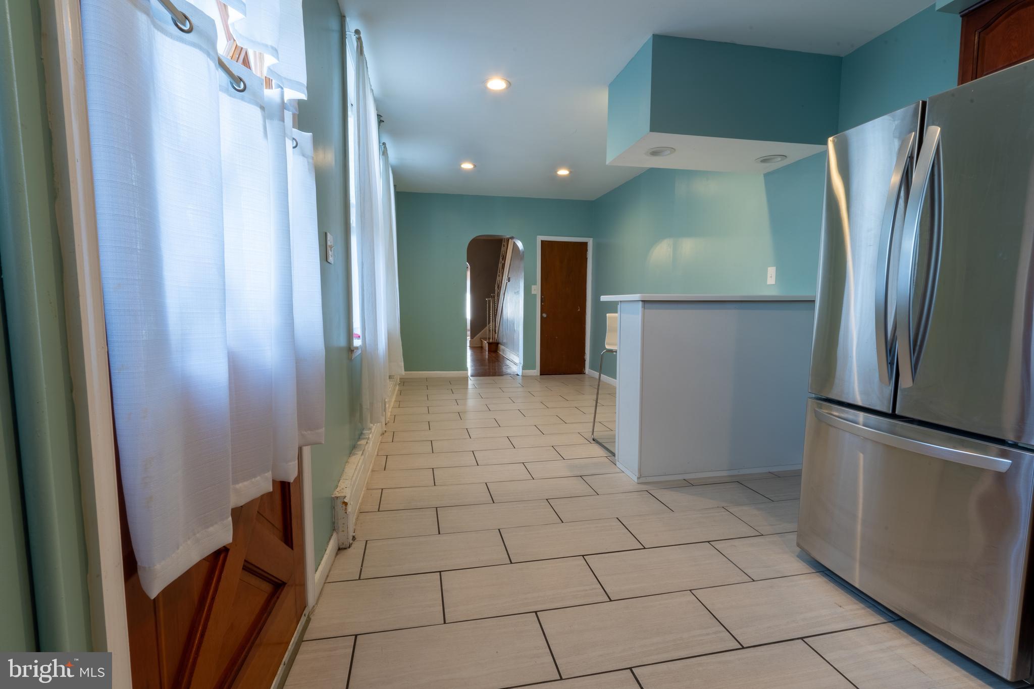 3618 Emerald Street Philadelphia, PA 19134 - Photo 27 of 34 a view of a refrigerator in kitchen and an empty room in wooden floor