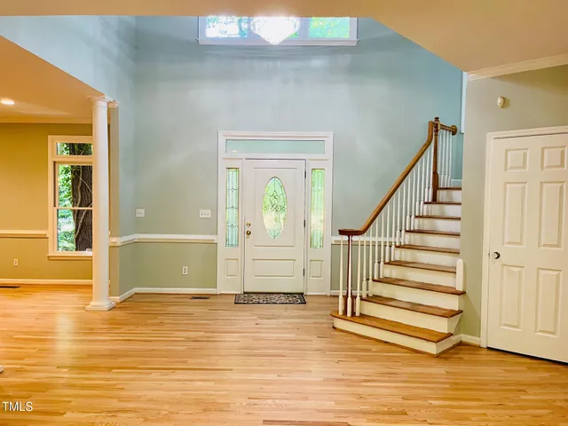 a view of an empty room with wooden floor and a bathroom