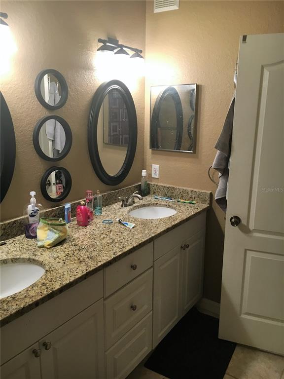 3355 South Kirkman Road, Unit 1324 Orlando, FL 32811 - Photo 8 of 19 a bathroom with a granite countertop sink and a mirror