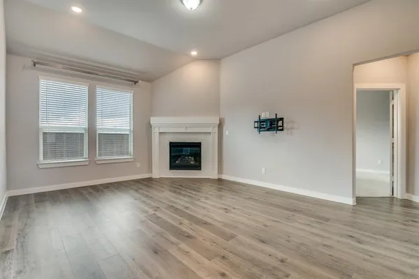 an empty room with wooden floor and fireplace