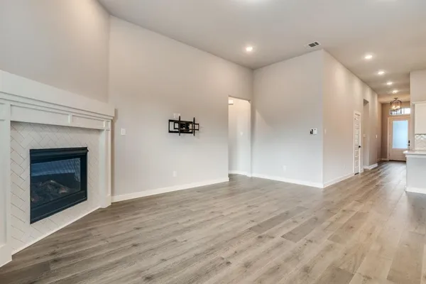 a view of an empty room with wooden floor and a fireplace