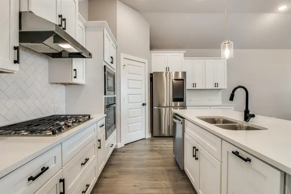 a kitchen with stainless steel appliances granite countertop a sink stove and refrigerator