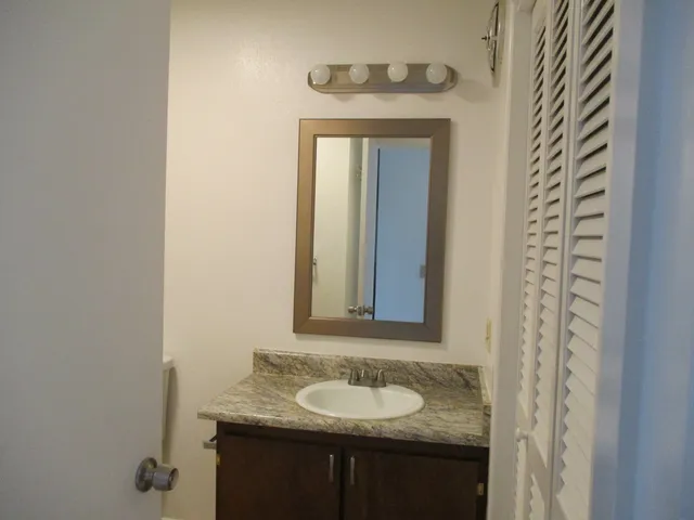a bathroom with a granite countertop sink and a mirror