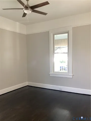 an empty room with wooden floor fan and windows