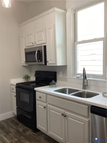 a kitchen with white cabinets sink and window