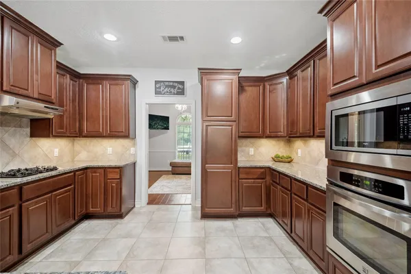 a kitchen with stainless steel appliances granite countertop wooden cabinets a stove top oven a sink and dishwasher