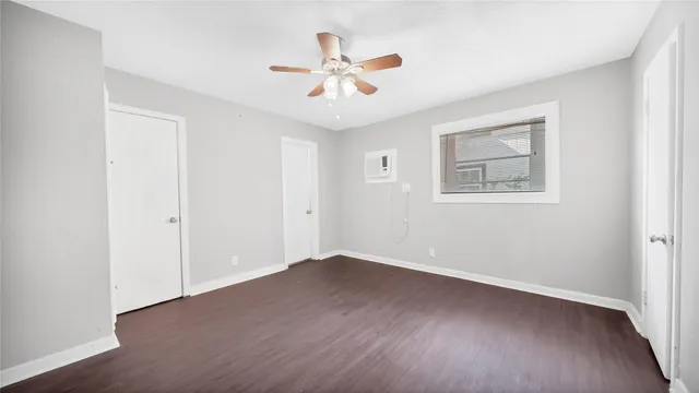an empty room with wooden floor ceiling fan and windows