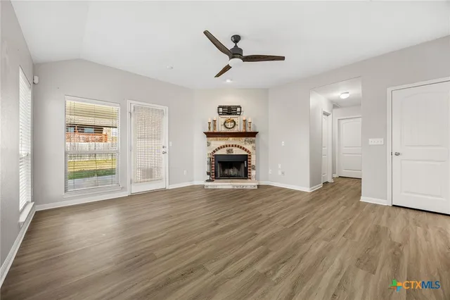 a view of a livingroom with wooden floor a ceiling fan and a window
