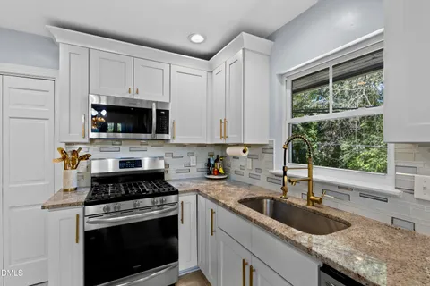 a kitchen with granite countertop a sink a stove and cabinets