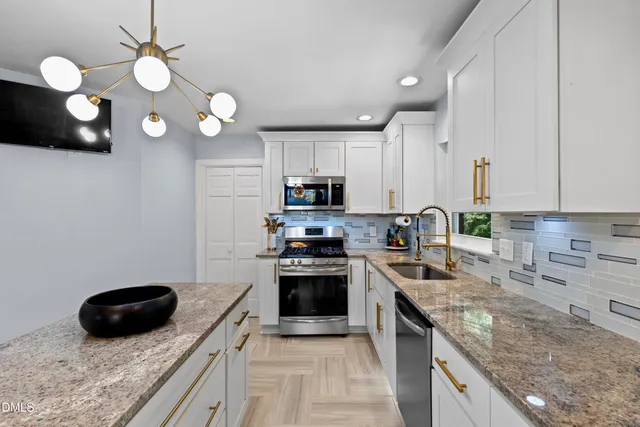 a kitchen with stainless steel appliances granite countertop a stove a sink a microwave oven a refrigerator and a stove