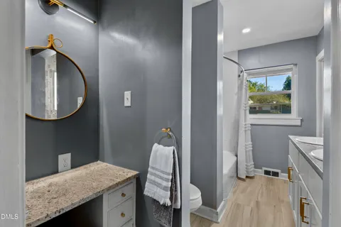 a bathroom with a granite countertop sink a mirror and a toilet