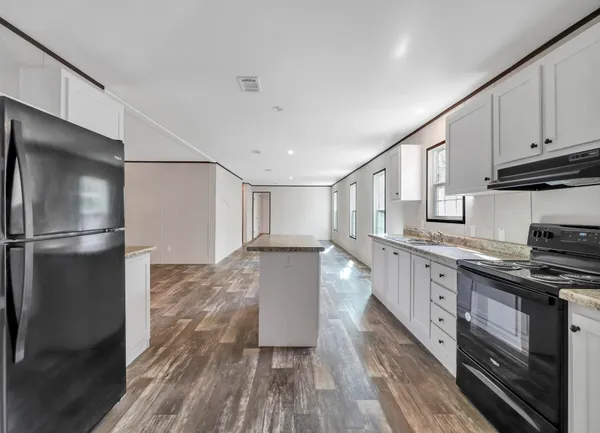 a kitchen with granite countertop a refrigerator stove and wooden floor