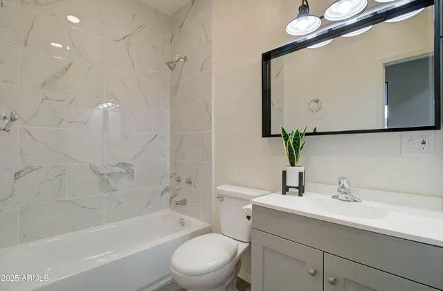 a bathroom with a bathtub shower sink vanity mirror and toilet