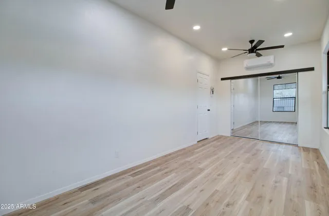 an empty room with wooden floor cabinet and windows
