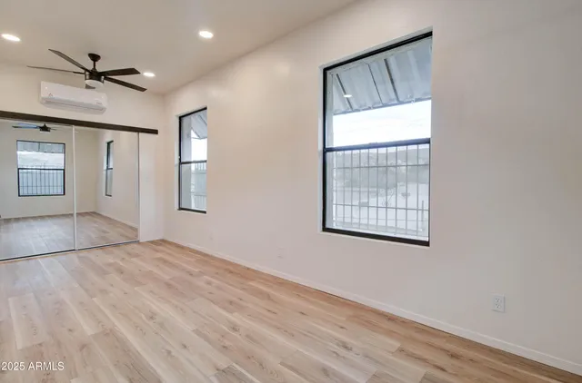 a view of empty room with wooden floor and fan