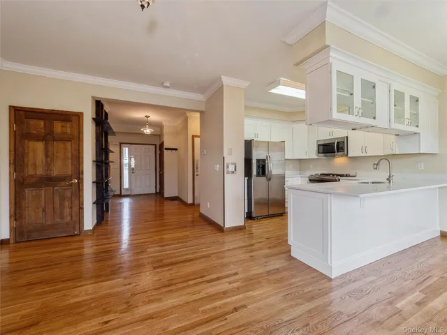 a view of kitchen with stainless steel appliances granite countertop a stove top oven a refrigerator and a cabinets with wooden floor