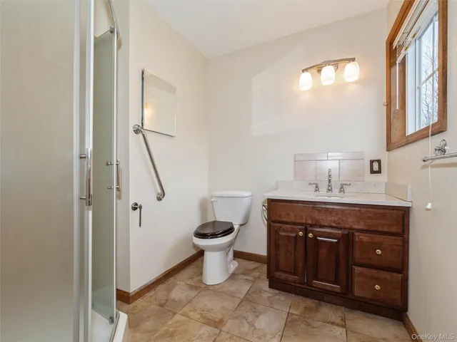 a spacious bathroom with a granite countertop toilet a sink and a mirror