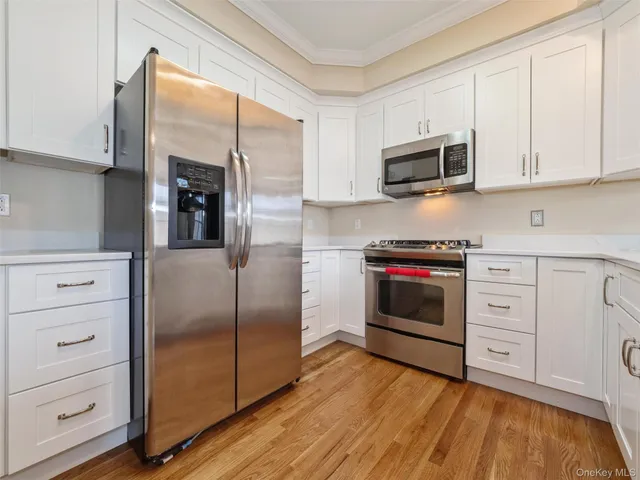 a kitchen with stainless steel appliances cabinets and a wooden floor