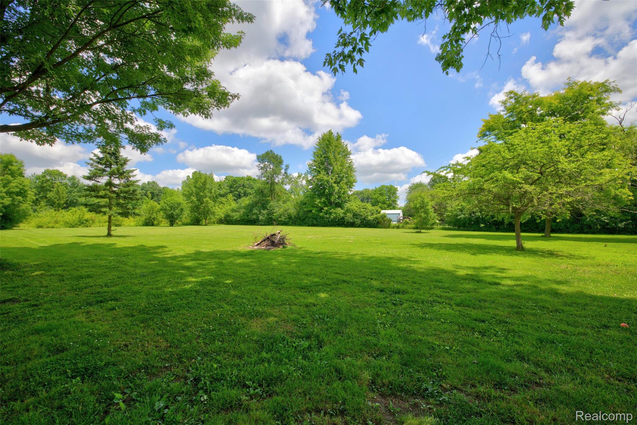 5244 Oleksyn Road Flint, MI 48504 - Photo 53 of 70 Expansive green lawn surrounded by mature trees, offering a clear blue sky with white clouds