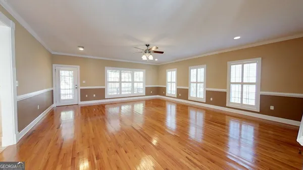 a view of an empty room with window and wooden floor