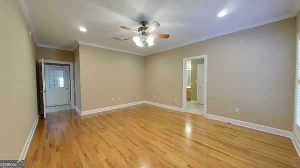 a view of an empty room with chandelier fan