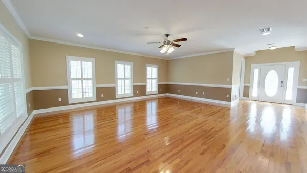 a view of an empty room with wooden floor and a window