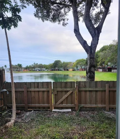 a view of a backyard with wooden fence and a large tree