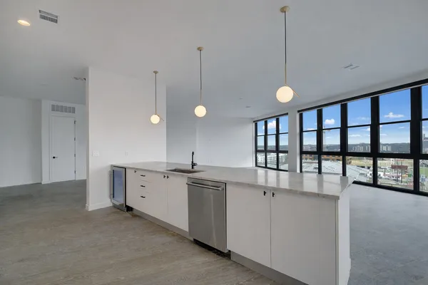 a large kitchen with granite countertop a sink and white cabinets