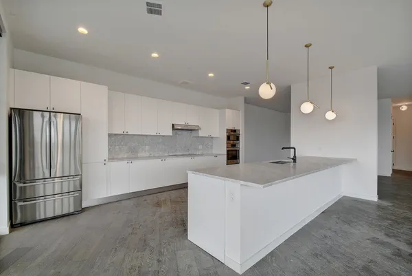 a large kitchen with kitchen island a stove a sink a center island a refrigerator and wooden floor