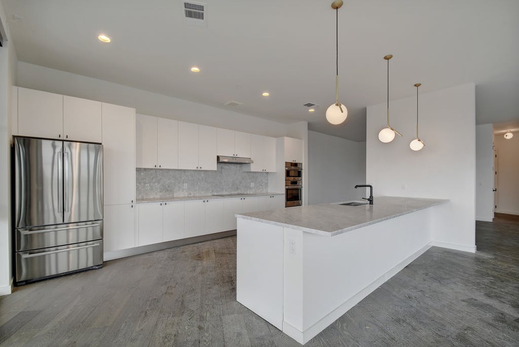 800 Embassy Drive, Unit 606 Austin, TX 78702 - Photo 9 of 38 a large kitchen with kitchen island a stove a sink a center island a refrigerator and wooden floor