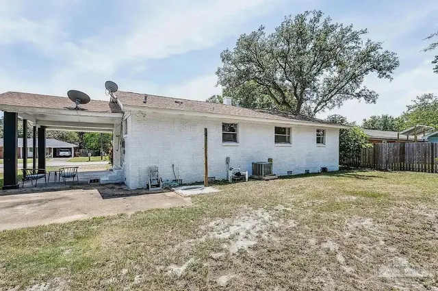 a backyard of a house with large trees and wooden fence