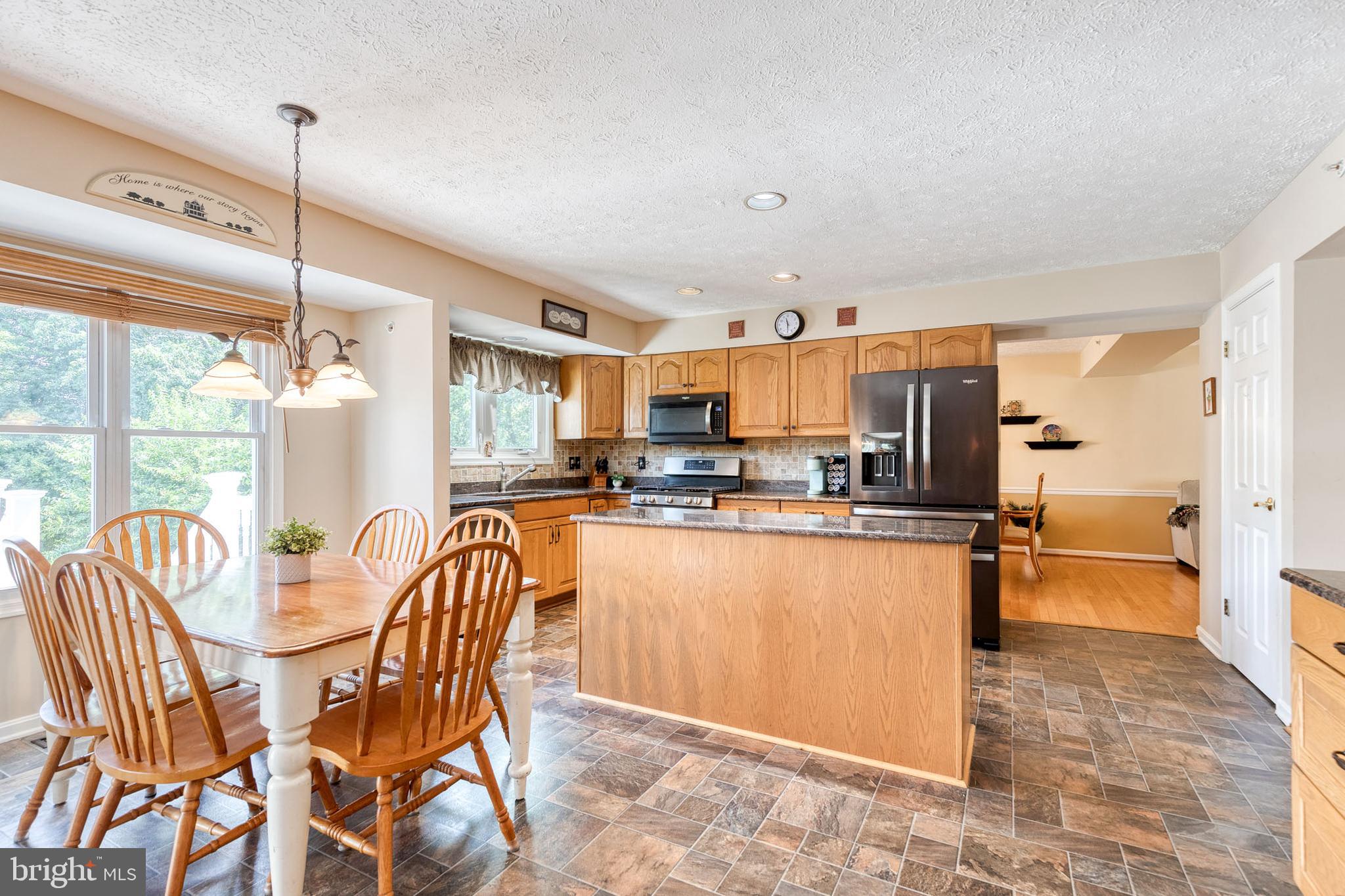 16 Perry Ridge Court Baltimore, MD 21237 - Photo 14 of 45 a kitchen with stainless steel appliances a refrigerator a sink dishwasher a dining table and chairs with wooden floor