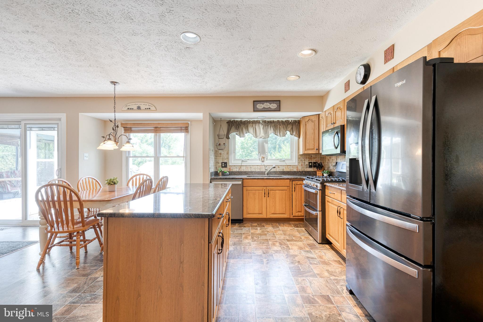 16 Perry Ridge Court Baltimore, MD 21237 - Photo 9 of 45 a kitchen with stainless steel appliances granite countertop a refrigerator a stove a dining table and chairs with wooden floor